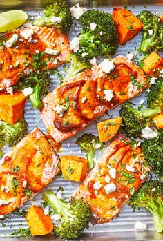 salmon and broccoli on a baking sheet with lemon wedges