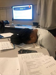 a woman sleeping on top of papers in front of a computer