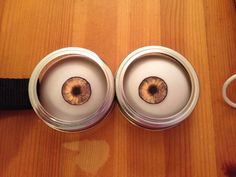 two tin cans with eyeballs in them sitting on a table