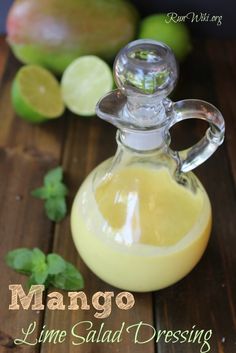 mango lime salad dressing in a small glass bottle on a wooden table next to fresh fruit