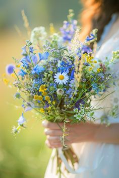 a woman holding a bouquet of blue and yellow flowers