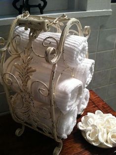 several white towels stacked on top of each other next to a bowl and towel rack