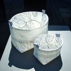 two white bowls sitting on top of a table covered in black and white cloths