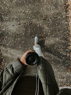 a person with headphones on is looking down at the ground while holding an object in their hand