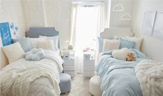 two beds in a bedroom with white and blue decor