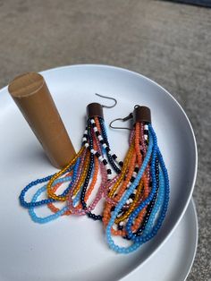 Beaded loop earrings made with size 11 glass seed beads. Orange, pink, blue and multi colored loops, 7 in all, six colors and one black and white harlequin strand. Bronze toned caps and wires. Bead loops are hand sewn on brain tanned hide piece then glued into the metal cap for the finished product. Total length including wire is 3.5 inches.  Custom color scheme orders welcome. Multicolor Czech Glass Beaded Earrings, Multicolor Dangle Beads With Ear Wire, Colorful Czech Glass Beaded Earrings, Multicolor Beaded Chain Dangle Beads, Multicolor Beaded Drop Earrings With Beaded Chain, Stitch Earrings, Brick Stitch Earrings, Loop Earrings, Glass Seed Beads