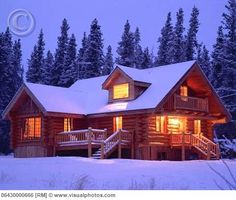 a log cabin lit up at night with snow on the ground and trees in the background