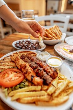 a plate full of food sitting on top of a table next to plates of fries and tomatoes