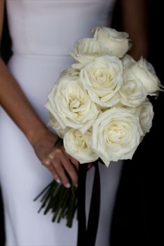 a bride holding a bouquet of white roses