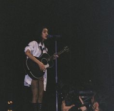 a woman standing next to a guitar on top of a stage