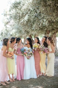 a group of women standing next to each other holding bouquets in front of trees