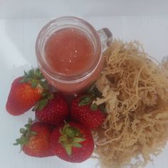 some strawberries are next to a jar of liquid