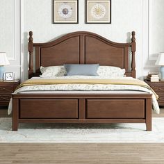 a large bed with drawers underneath it in a white and beige bedroom setting, along with two lamps on either side of the bed