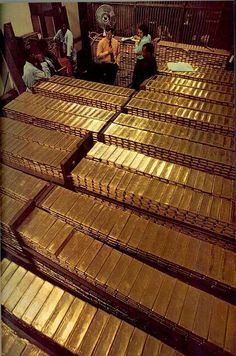 several stacks of gold bars are stacked on top of each other in a room filled with people