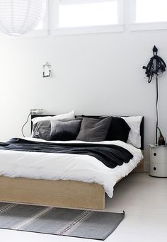 a bed room with a neatly made bed next to a window and a rug on the floor