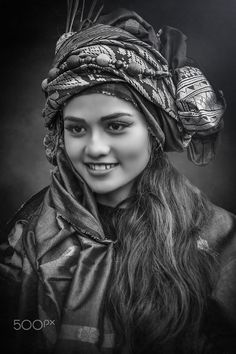 a woman with long hair wearing a headdress and smiling at the camera in black and white