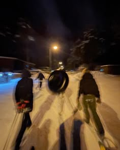 two people riding skis down a snow covered slope at night with lights shining on them