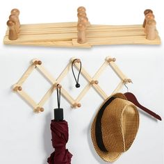 a hat and umbrella hang on a coat rack with pegs attached to the wall