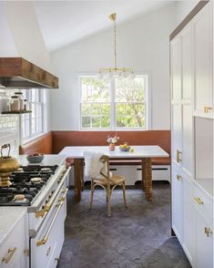 a kitchen with an oven, table and chairs in it