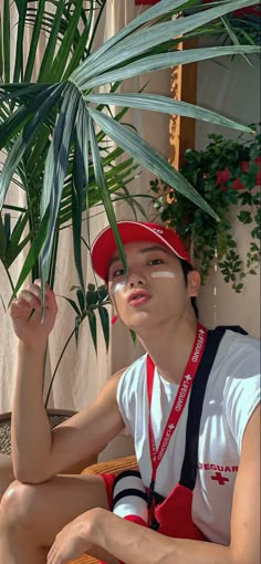 a young man sitting on the ground next to a plant