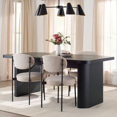 a dining room table with four chairs and a vase on the table next to it