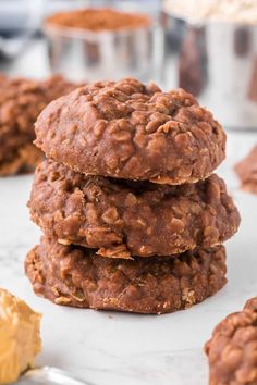 three cookies stacked on top of each other with peanut butter in the background and one cookie missing