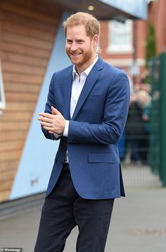 a man in a blue jacket and white shirt is standing with his hands folded out