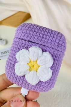 a hand holding a small crocheted cell phone case with a flower on it