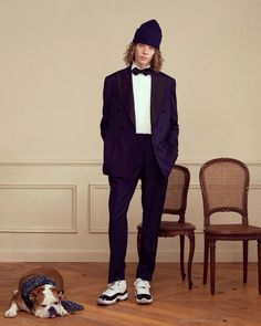 a man in a tuxedo and hat standing next to a dog on the floor