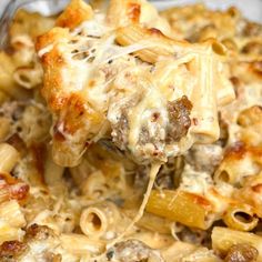 a spoon full of pasta with meat and cheese on it in a casserole dish