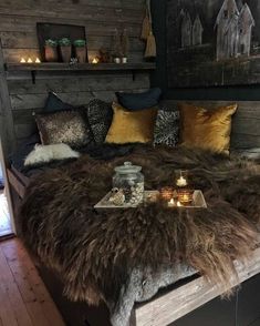 a bed with lots of pillows on top of it and some candles in the middle