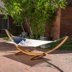 a white hammock sitting on top of a wooden stand next to a brick building