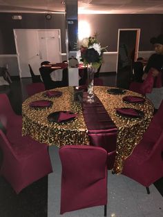 the table is set up with red chairs and leopard print cloths, along with a vase filled with flowers