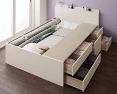 a bed with drawers underneath it in a room next to a window and wooden floor