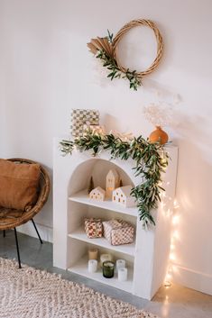 a white fireplace with greenery on the mantle and lights around it in a living room