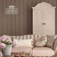 a living room filled with furniture and flowers on top of a wooden table next to a white cabinet