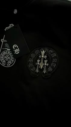 a black shirt with silver designs on it and a tag attached to the front pocket