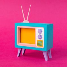 an old fashioned tv sitting on top of a wooden stand in front of a pink background