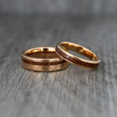 two gold wedding rings sitting on top of a wooden table