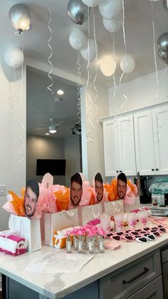 four men are sitting in front of a table with cake and balloons hanging from the ceiling