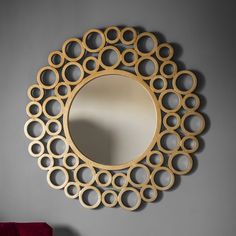 a circular mirror hanging on the wall next to a table with a vase in front of it