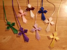 several different colored crosses hanging from strings on a table