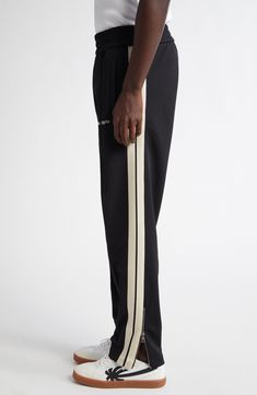 Francesco Ragazzi draws inspiration from vintage Americana aesthetics with these sporty side-striped trousers designed to mimic the appearance of varsity track pants. Elastic waist Front welt pockets Zip cuffs 100% polyester Hand wash, dry flat Made in Italy Designer Clothing Sporty Streetwear Pants With Contrast Trim, Sporty Pants With Contrast Trim For Streetwear, Sporty Black Pants With Contrast Trim, Striped Trousers, Trouser Design, Pants Elastic Waist, Vintage Americana, Classic Logo, Palm Angels