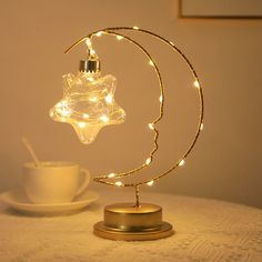 a lamp that is on top of a table next to a cup and saucer