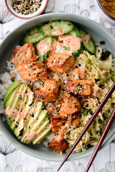 a bowl filled with rice, shrimp and cucumber next to chopsticks