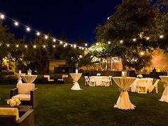 tables and chairs are set up in the yard for an outdoor dinner party at night