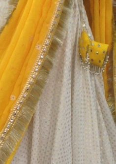 Haldi yellow lehenga with mirror work. The blouse is made of rawsilk with flutter sleeves in chiffon and all over mirror work. Skirt is made of brocade and has wide mirror work borders. Chiffon dupatta with sequins and mirror work. The dress will be made to order in your size. I'll send you a measurement sheet once you order for the measurements. Dress can be created in any color as the fabric is custom dyed. Please convo me if you have any questions or need any customisation. White And Yellow Lehenga For Haldi, Pre-draped Anarkali Saree With Gota Work, White Pre-draped Saree With Gota Work For Navratri, White Anarkali Pre-draped Saree With Dupatta, White Pre-draped Saree With Sheer Dupatta For Eid, Yellow Pre-draped Saree With Mirror Work For Navratri, Yellow Mirror Work Pre-draped Saree For Navratri, Eid Pre-draped Kundan Saree With Dupatta, Eid Kundan Pre-draped Saree With Dupatta