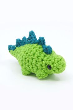 a crocheted green and blue toy fish sitting on top of a white surface