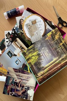 an open photo album sitting on top of a wooden table next to scissors and glue