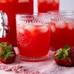 three glasses filled with red liquid and strawberries